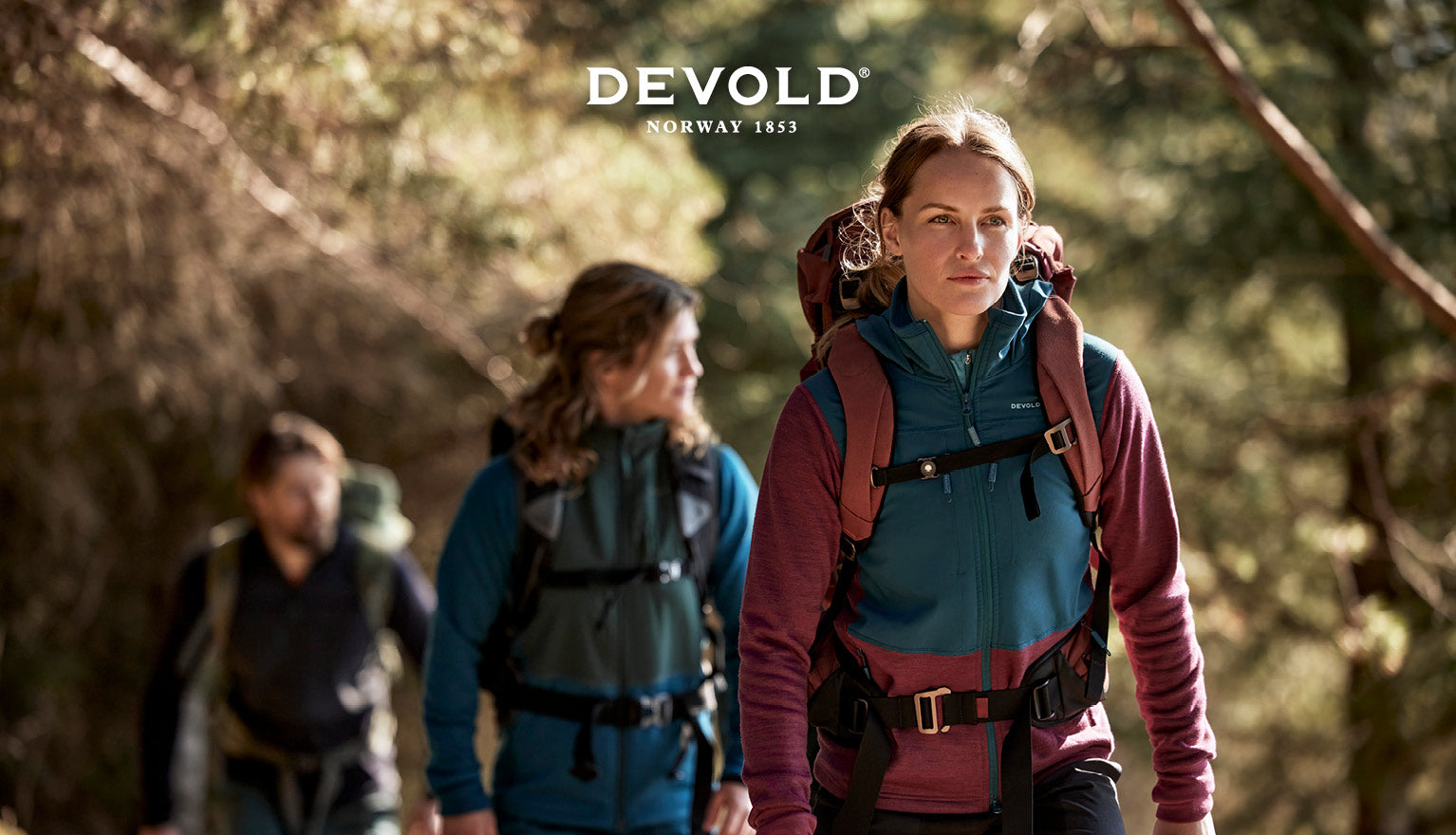 Devold Marketing Kampagne: 3 Personen laufen mit Wanderausrüstung durch den Wald.