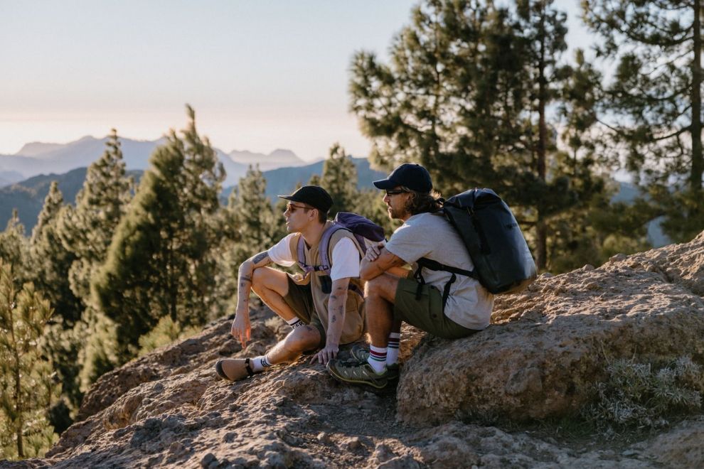 2 Personen sitzen auf einem Felsen am im Wald und schauen in die Ferne.