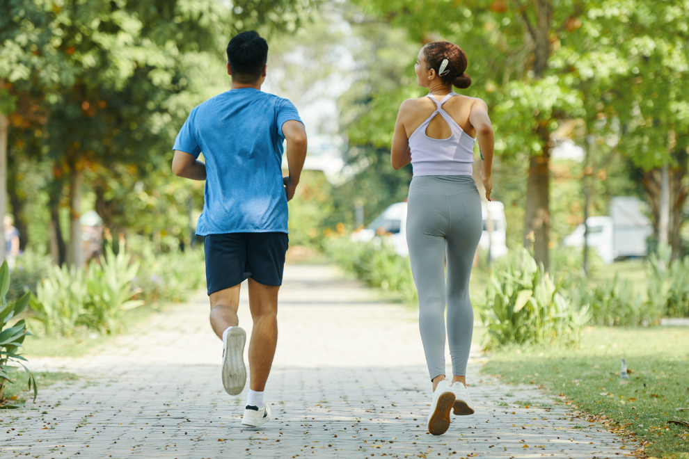 1 Mann und eine Frau joggen auf einem Fußgängerweg.