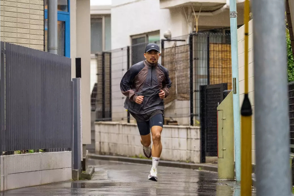 Mann läuft in einer Gasse mit New Balance Bekleidung.