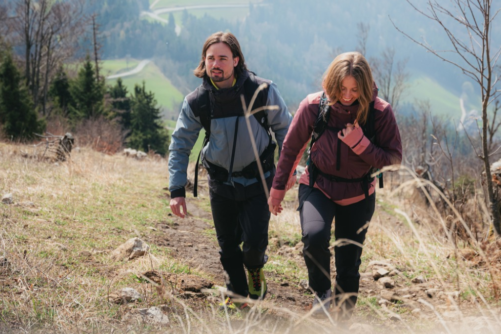 2 Personen sitzen auf einem Felsen am im Wald und schauen in die Ferne.