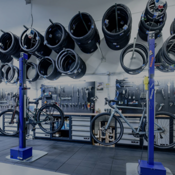 2 Fahrräder sind auf Hebebühnen in der Fahrrad-Werkstatt von Sport Kuhn fixiert. Werkzeug und Fahrrad-Mäntel befinden sich im Hintergrund.